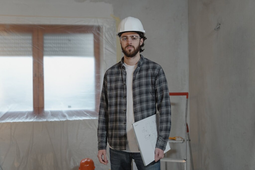 A man with a white helmet and a shirt holding a paper