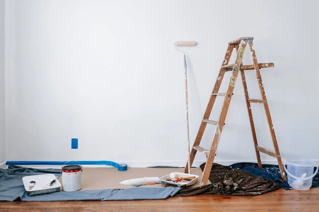 A brown wooden ladder beside painting materials.