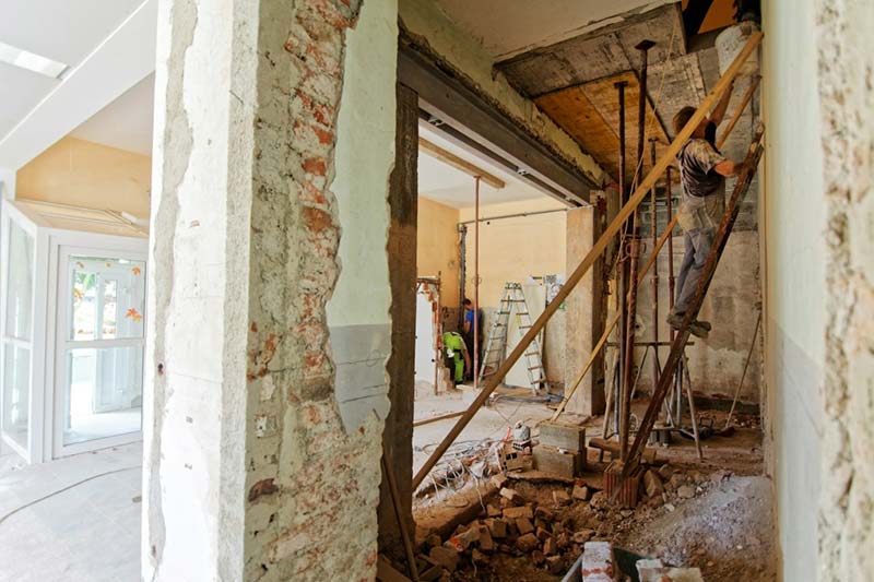 Alt-tag: Man climbing on a ladder inside a house.